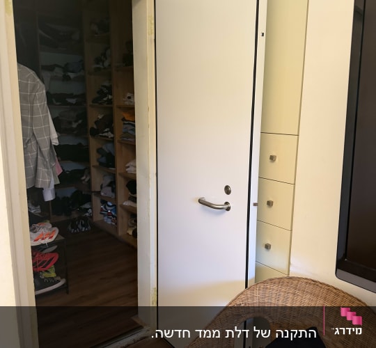 דלת לבנה פתוחה עם ידית כסופה ליד ארון בגדים